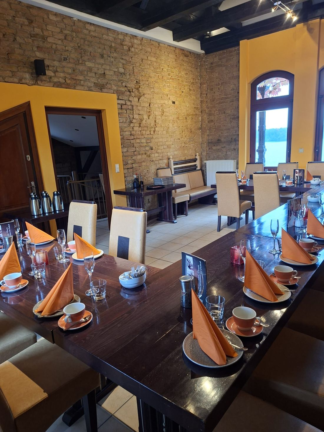 Festsaal oben: lange Tafel, gedeckt mit Kaffeegedecken, durch die Fenster der See