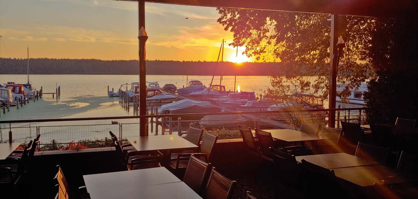Sonnenuntergang über dem Bootshafen, gesehen von der überdachten Terrasse