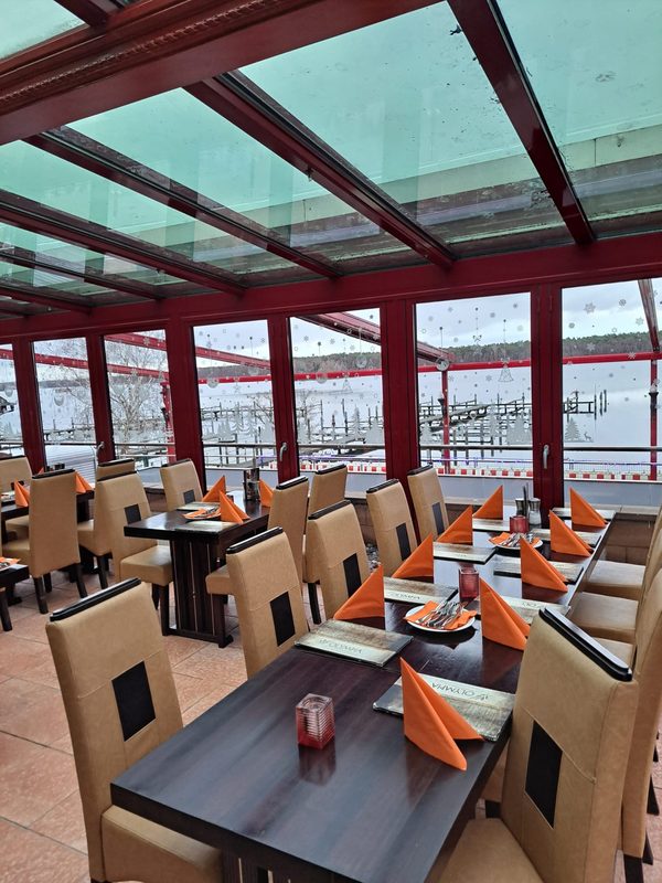Gedeckter Tisch im Wintergarten, durch die Fenster der Bootshafen