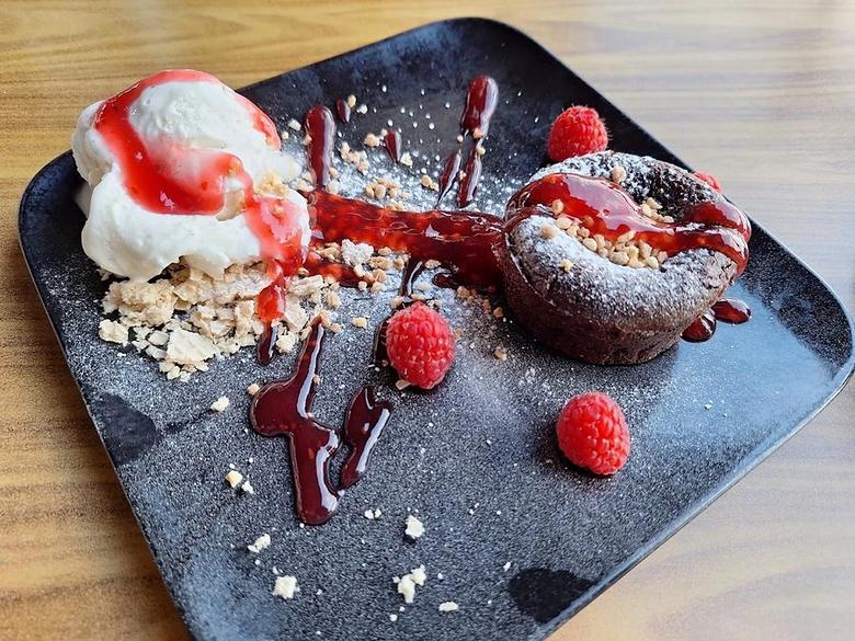 Schokoladenkuchen mit Vanilleeis und frischen Himbeeren